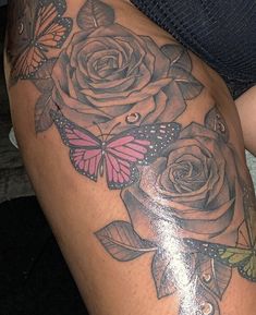 a woman's thigh with roses and butterflies on her thighs, as well as a butterfly tattoo