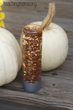 two white pumpkins sitting next to each other on a wooden table with glitter in them