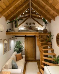 a living room filled with furniture next to a wooden stair case under a roof covered in lights