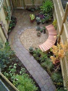 a small garden with lots of plants and rocks in the center, surrounded by wooden fences