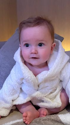 a baby wrapped in a white towel on top of a bed