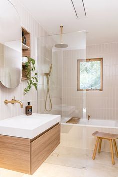 a bathroom with a sink, mirror and bathtub next to a bench in the corner