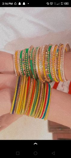 a woman's hand holding several different colored bracelets on top of each other