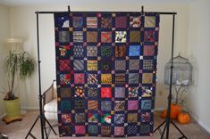 a quilt is displayed on a tripod in a room