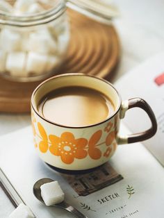 a cup of hot chocolate and marshmallows on a table next to an open book