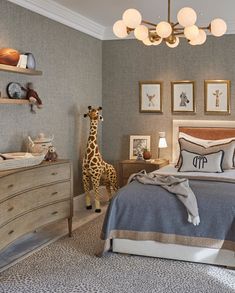 a giraffe is standing next to a bed in a room with gray walls