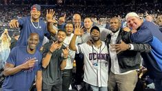 the men are posing for a photo at a basketball game with their hands in the air