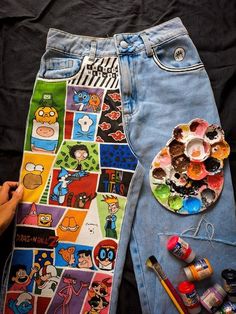 a pair of jean shorts with cartoon characters on them and paintbrushes next to it