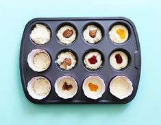 cupcakes with different toppings sitting in a muffin tin on a blue surface