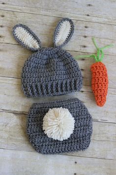 two crocheted hats and a carrot on a wooden surface