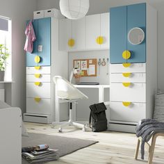 a white and blue room with yellow accents on the cabinets, desk and chair in it