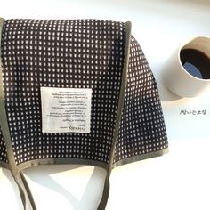 a black and white checkered purse next to a cup of coffee