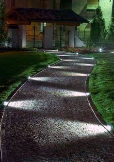 a pathway that is lit up at night in front of a house