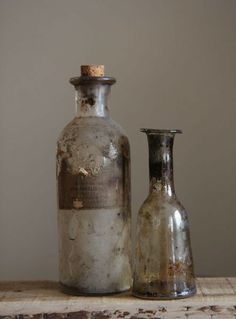 two old glass bottles sitting on top of a wooden table