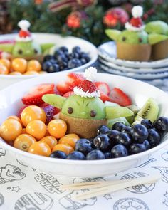 a bowl filled with fruit and vegetables on top of a table next to other plates