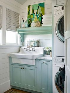 a washer and dryer in a small room with blue cabinets, white walls and wood floors