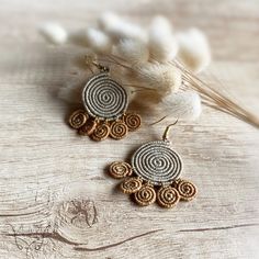 a pair of earrings sitting on top of a wooden table next to some white flowers