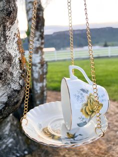 a tea cup and saucer hanging from a tree