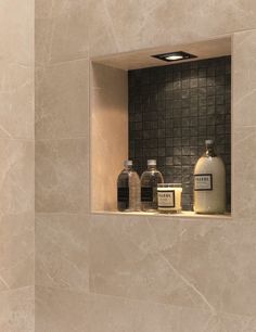 there is a bathroom with marble walls and tile on the wall, along with soap bottles