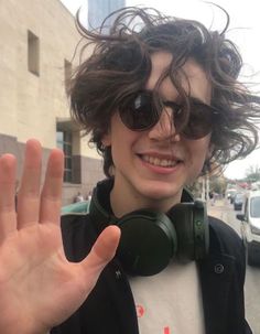 a young man wearing headphones and holding his hand up in front of the camera