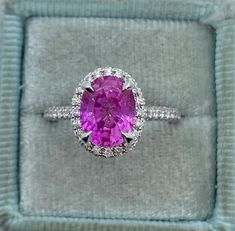 an oval shaped pink sapphire and diamond ring in a velvet box