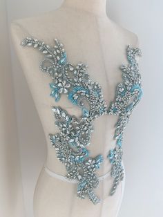 a white mannequin with blue and silver beading on it's back