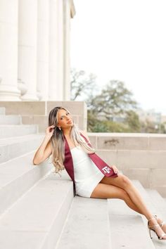 a beautiful woman sitting on the steps of a building wearing a white and maroon dress