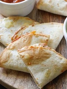 quesadillas with guacamole and salsa on a wooden platter