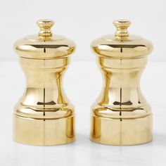 two golden salt and pepper shakers on a white surface