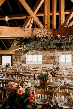 the tables are set with flowers and greenery hanging from the rafters above them