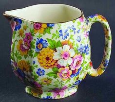 a colorful flowered pitcher sitting on top of a table