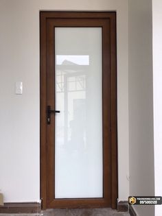 an empty room with a wooden door and white walls in front of the glass doors