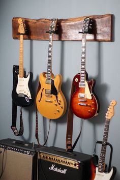 guitars are hanging on the wall next to amps