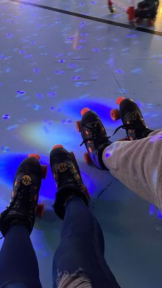 two people riding skateboards on top of an ice covered floor with blue and red lights