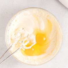 two eggs are being mixed in a bowl with a whisk on the side