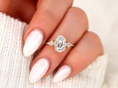 a woman's hand with white manicured nails and a ring on her finger