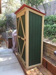 a green and yellow storage shed sitting on top of a wooden deck