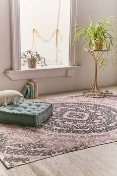 a living room with a rug, chair and potted plant in the window sill