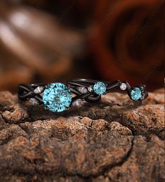 two rings with blue topaz and white diamonds on them, sitting on a rock