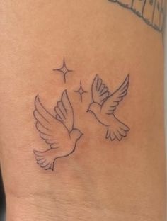 a small tattoo on the leg of a woman with two birds flying above her head