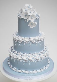 a three tiered blue wedding cake with white flowers