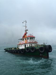 a tug boat in the middle of the ocean with large tires on it's side