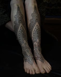 the legs and feet of a person with tattoos on their ankles, both have intricate designs