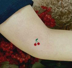 a small cherry tattoo on the left arm