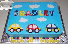 a birthday cake with three cars on it and the words happy 1st birthday written in large letters