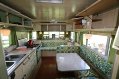 the interior of an rv with green and blue decor on the walls, windows, and counters