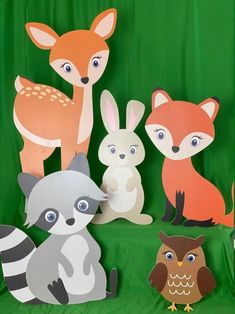 some paper animals are sitting on a green cloth covered surface with an owl, raccoon, and fox cut out