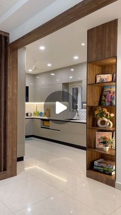 an open living room and kitchen area with white tile flooring, wooden bookcases