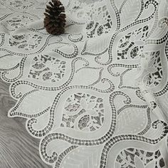 a pine cone sitting on top of a white doily with an intricate lace design