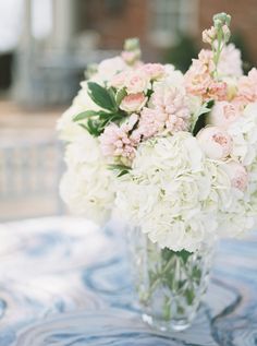 a vase filled with lots of white and pink flowers on top of a table cloth